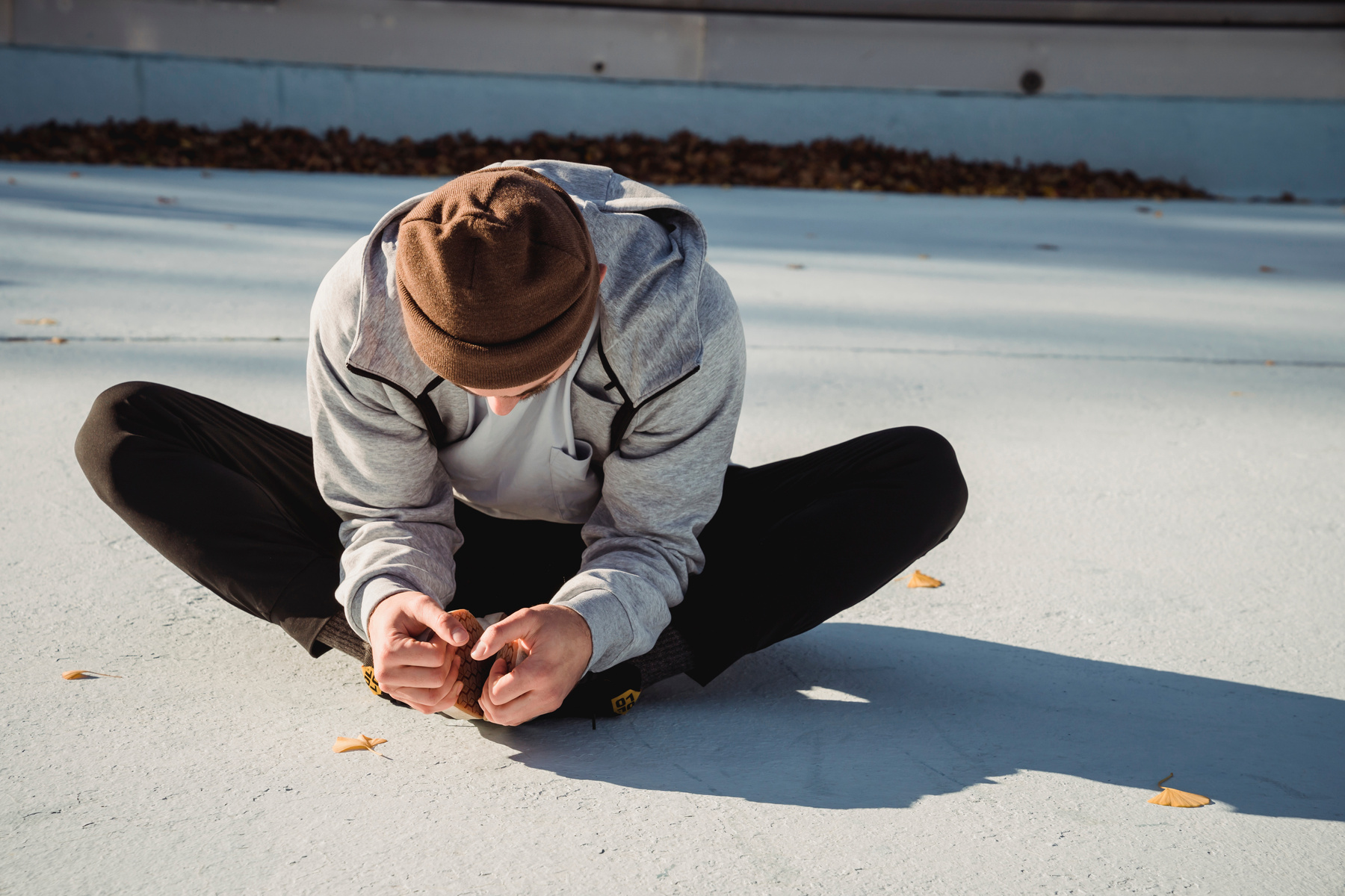 Unrecognizable athlete stretching legs on pavement in sunlight